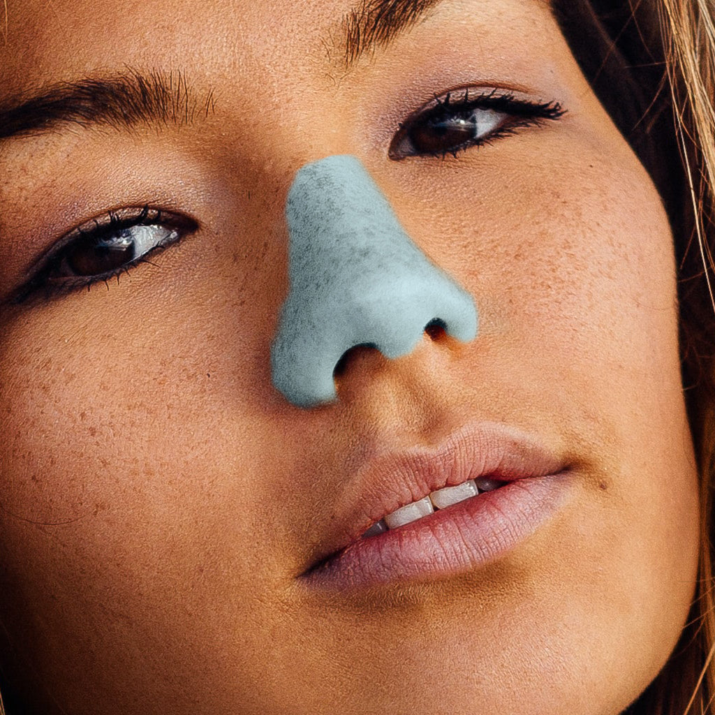 Young women with freckles wearing light blue NöZ sunscreen on her nose while smirking